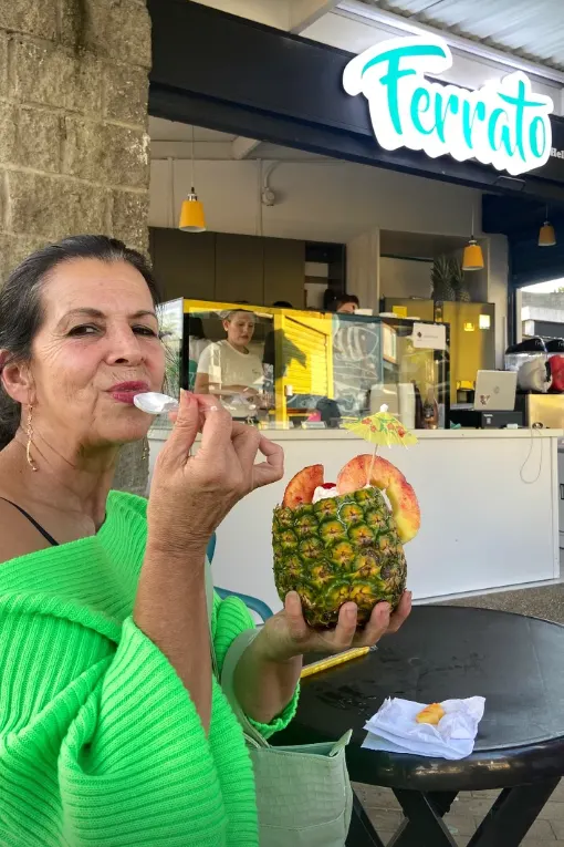 Una clienta con su helado servido en piña, en la puerta de la heladería